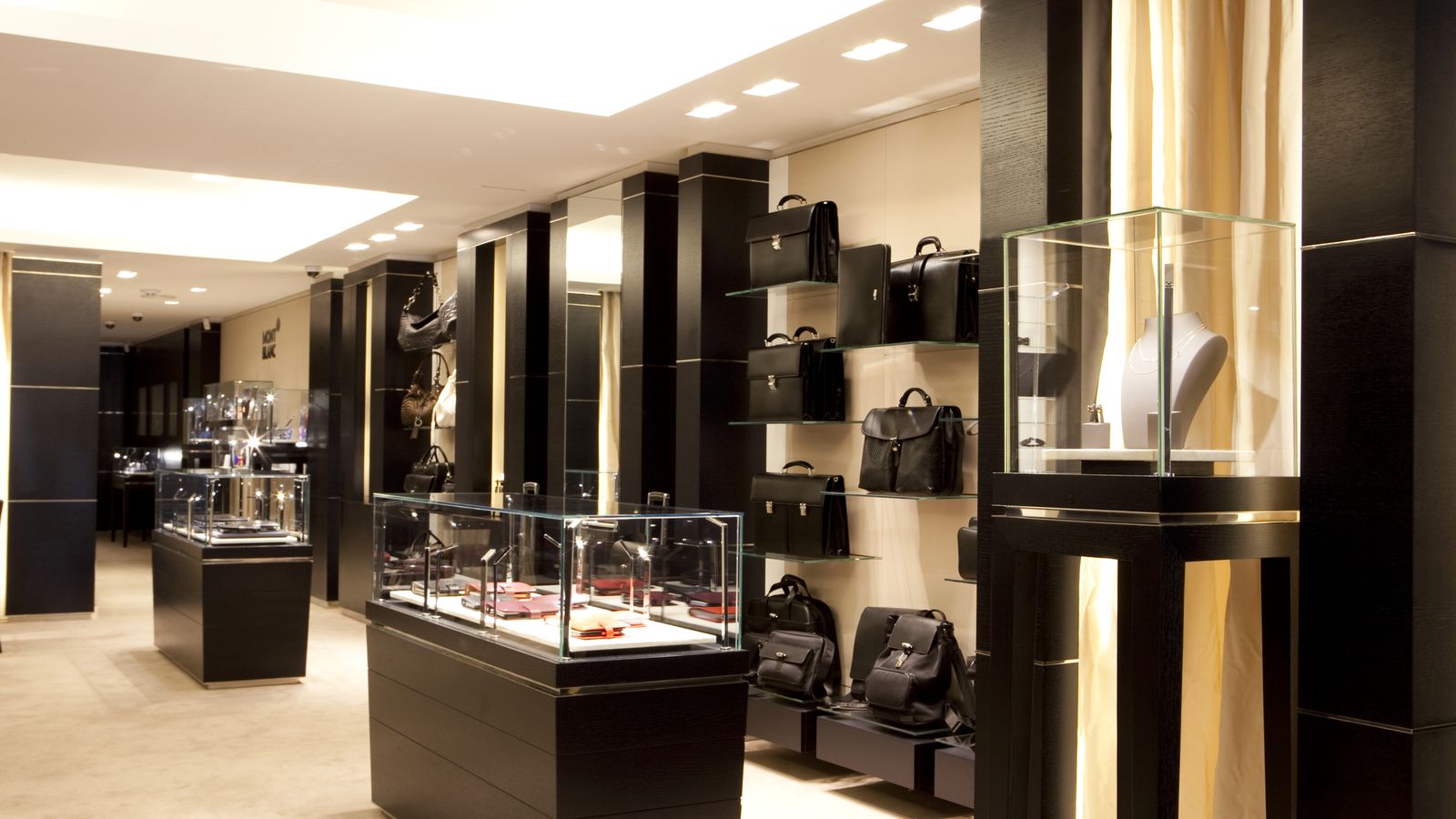 Interior de boutique Montblanc con vitrinas y revestimientos de madera oscura.